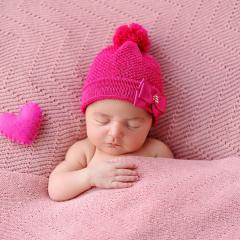 Baby wearing pink beanie with little stuffed heart on the left