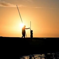 Silhouette of two people spear fishing