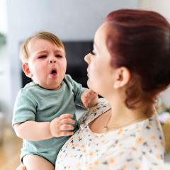 Coughing baby being held by mother